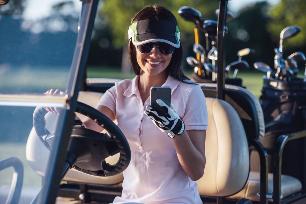 A woman checking her phone while seated in a golf cart
